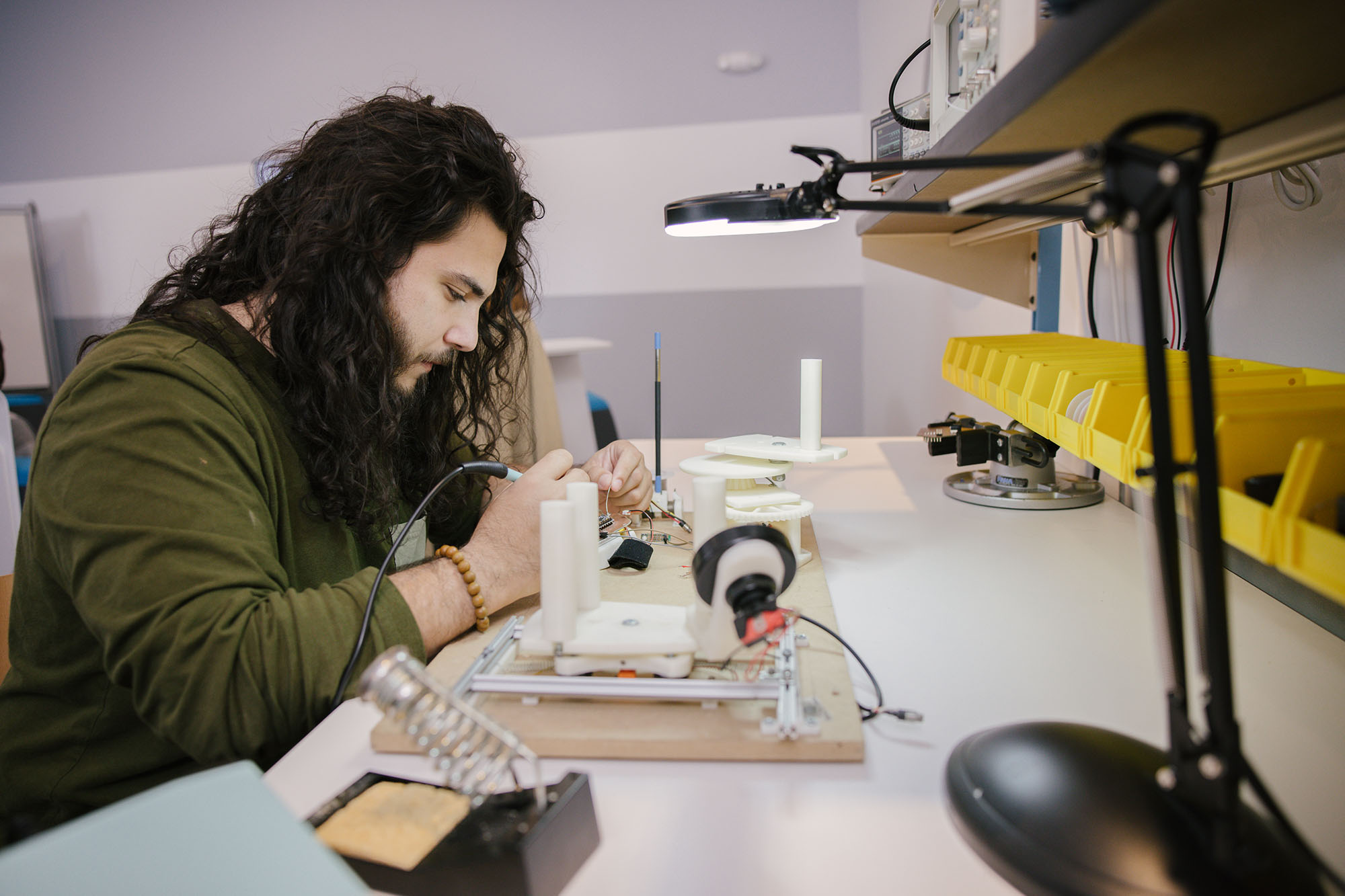 A student at a workbench working on a electronic component