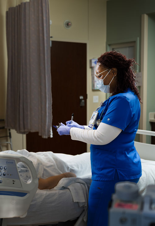 image of nurse at patient's bedside wearing a mask