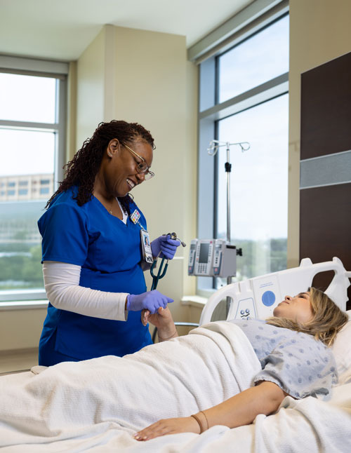 nurse smiles at patient in hospital room