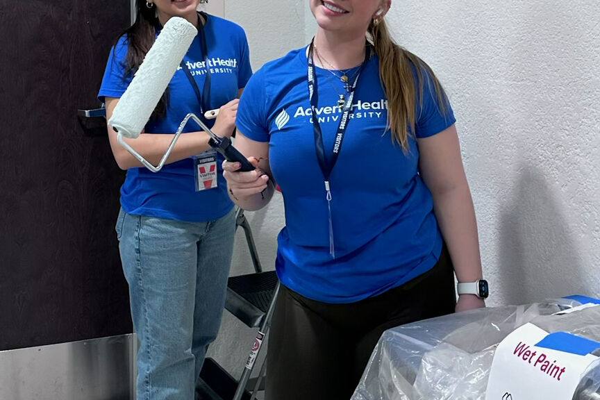 Two students smiling and painting for all AHU service day