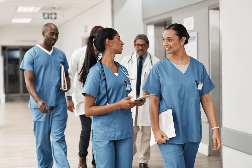 A group of nurses walking down a hospital floor hallway