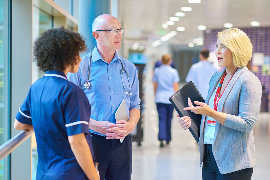 A hospital administrator converses with a doctor and nurse