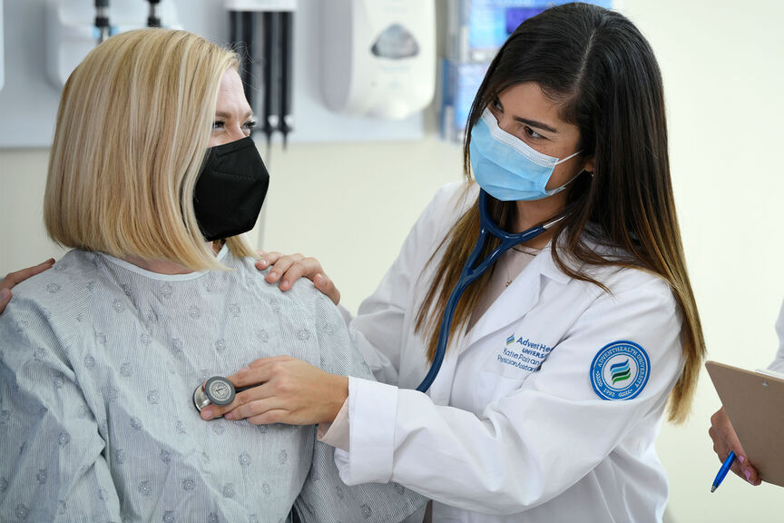 A female physician assistant student using a stethoscope on a patient