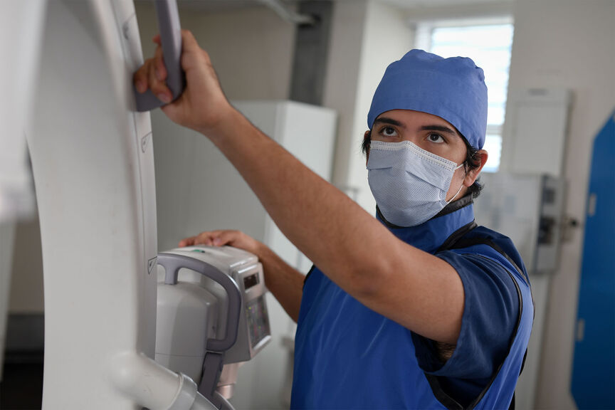 A radiography student positioning the arm of an x-ray machine