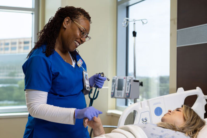 nurse smiles at patient in hospital room