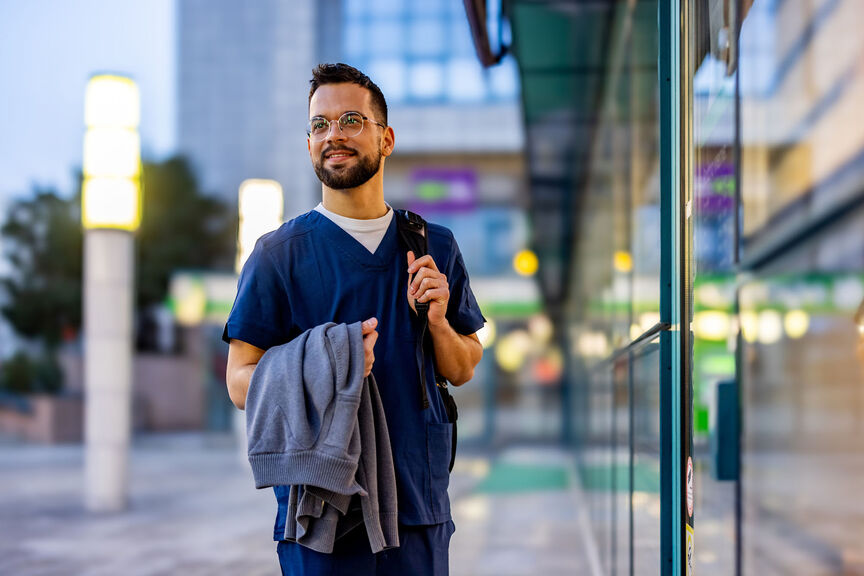 A male travel nurse standing outside a buidling