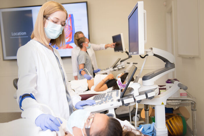 A female sonography student scanning another student