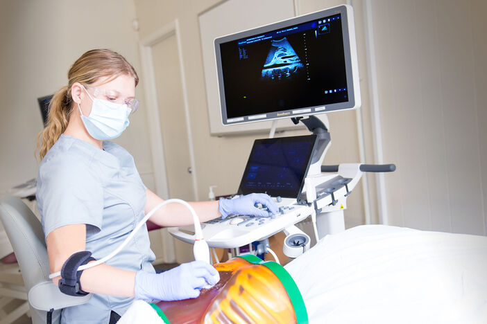 A female sonography student scanning an anatomy phantom