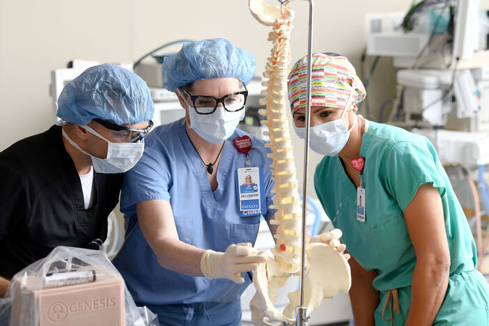 A faculty member demonstrates a procedure on the spine for students in the skills lab