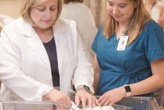 A nursing faculty member teaching skills to a student on an infant simulator