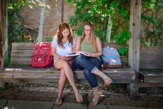 2 female students studying together on a bench outdoors