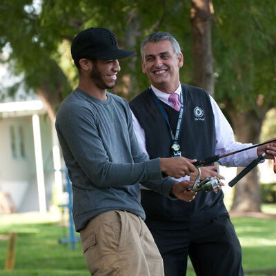 A student fishing with a chaplain at AHU's lake