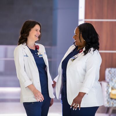 nurses in hallway smiling at each other
