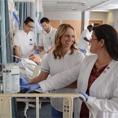 Students practicing in the nursing lab under the supervision of a faculty member