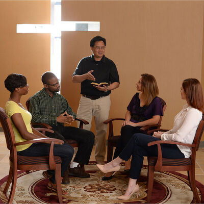 A group of students participating in bible study with a staff member in the chapel