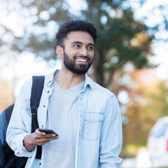 A middle-eastern male student walking outside on campus