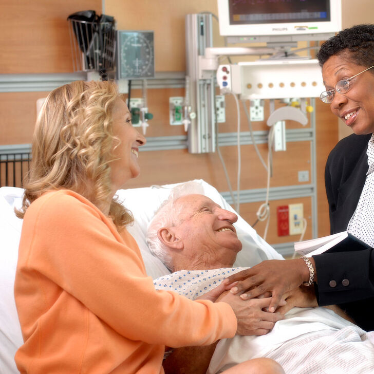 A hospital chaplain meets with a patient and family member