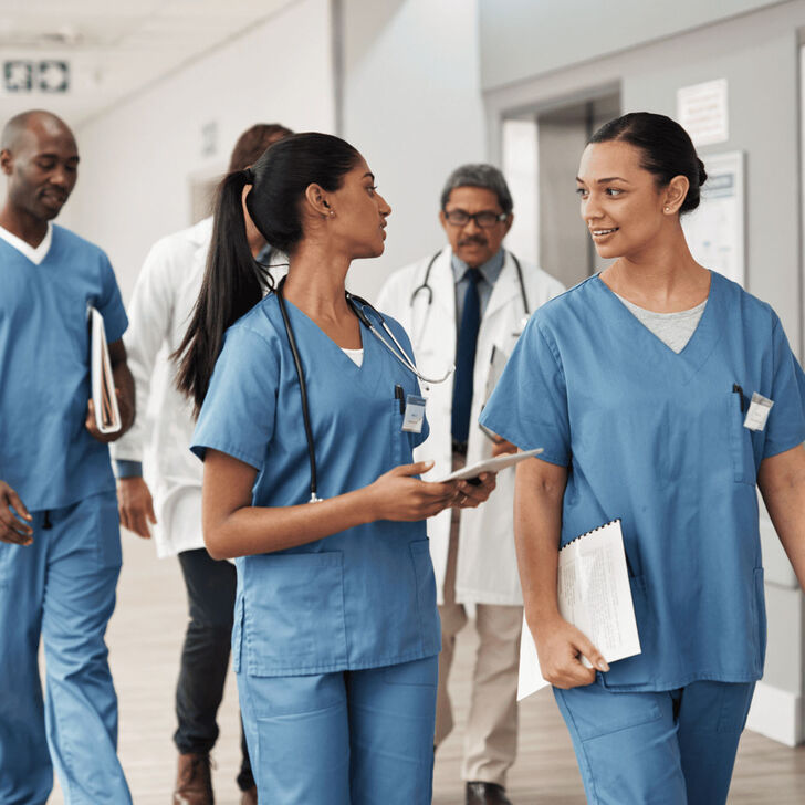 A group of nurses walking down a hospital floor hallway
