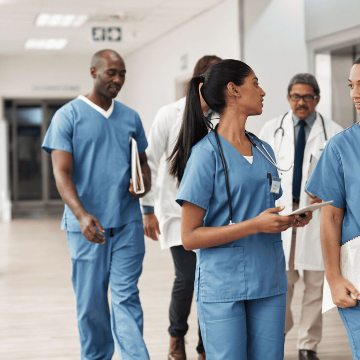 A group of nurses walking down a hospital floor hallway