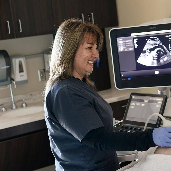A sonographer performs a scan on a pregnant woman