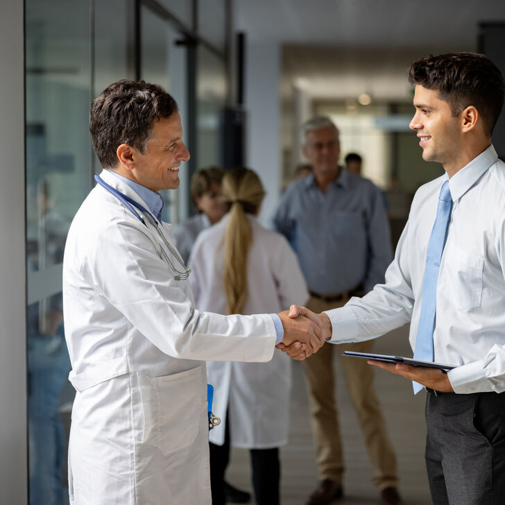 A doctor and healthcare administrator shake hands