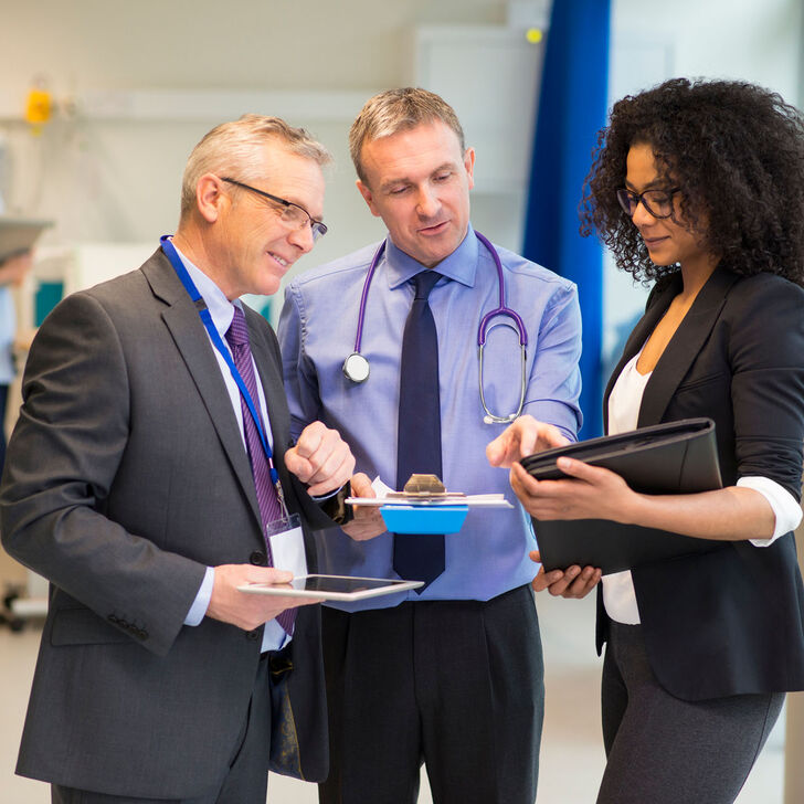 A doctor converses with healthcare consultants in a hospital