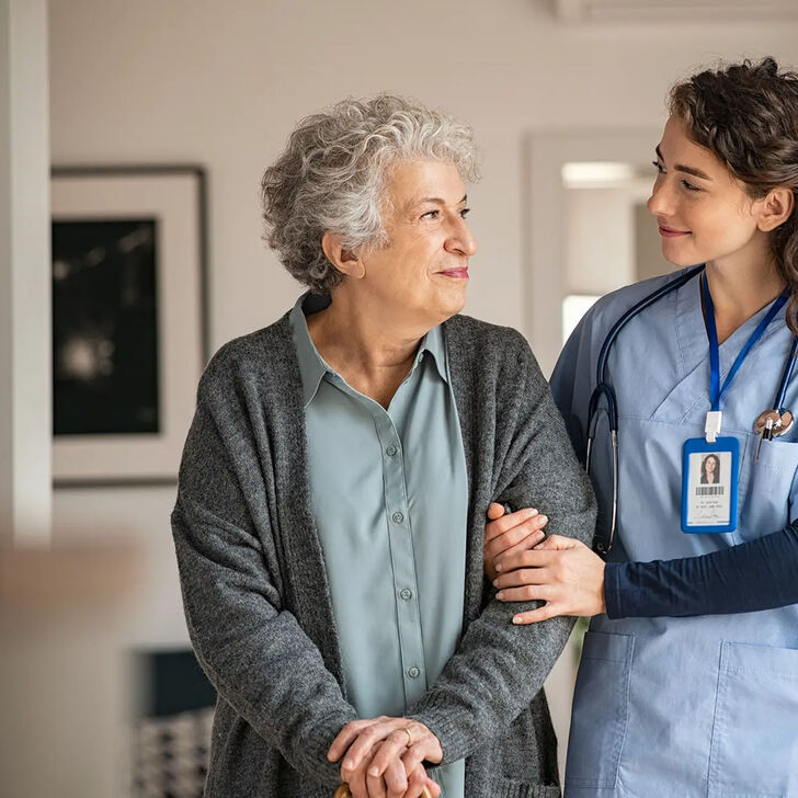 A health care worker assists and elderly patient