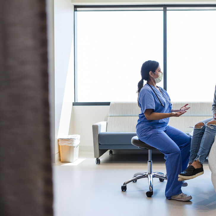 A nurse speaks with a patient in an exam room