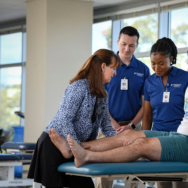 Physical therapy faculty and students practicing on patient table