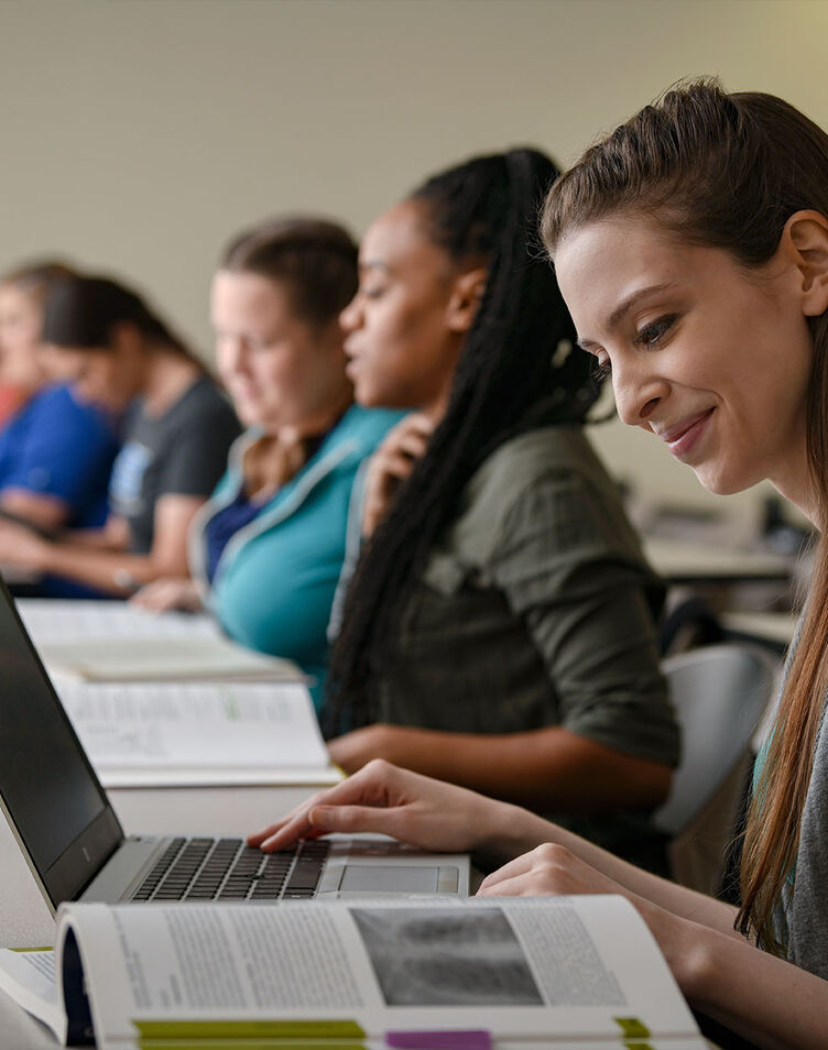 A female student works on her laptop in a classroom
