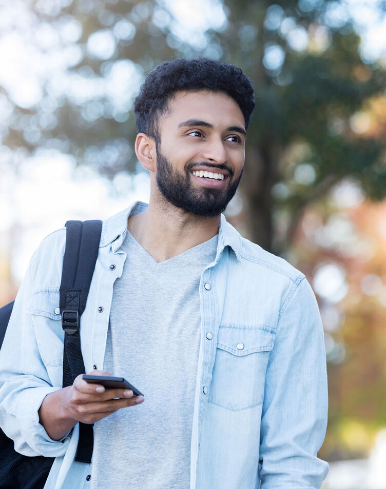 A middle-eastern male student walking outside on campus